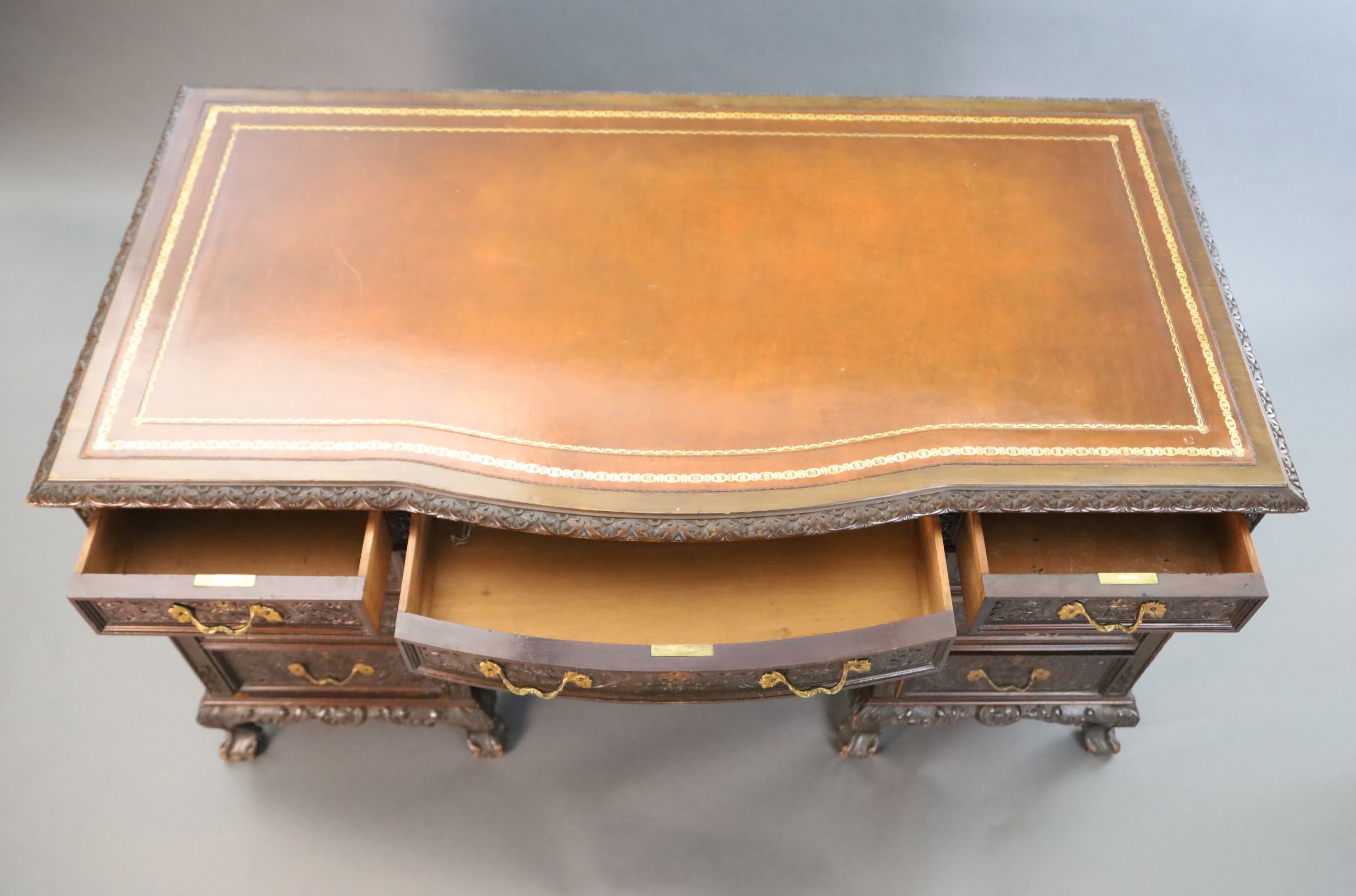 An Edwardian foliate carved mahogany serpentine kneehole desk, W.4ft 6in. D.2ft 5in. H.2ft 6in.